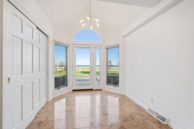 7515 N Beach Dr, Fox Point, WI 53217 - entryway with a chandelier, a water view, light marble finish floors, baseboards, and high vaulted ceiling