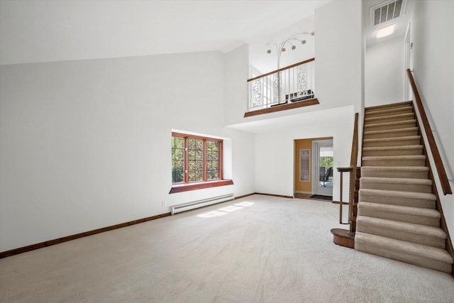 1401 Scenic Dr, Hubertus, WI 53033 - unfurnished living room with baseboard heating, stairway, baseboards, a towering ceiling, and carpet flooring