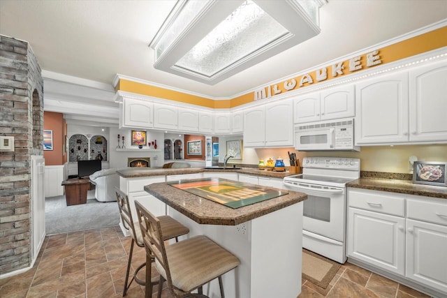 1401 Scenic Dr, Hubertus, WI 53033 - kitchen with white appliances, a kitchen breakfast bar, stone finish flooring, a lit fireplace, and wainscoting