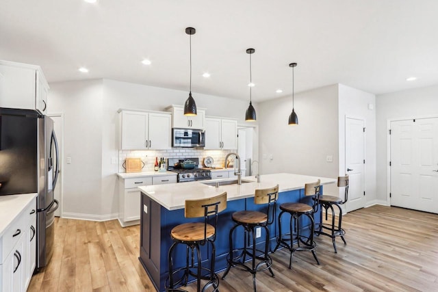 W139S9977 Jay Dr, Muskego, WI 53150 - kitchen featuring stainless steel appliances, light wood finished floors, decorative backsplash, a breakfast bar, and light countertops