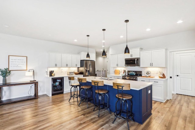 W139S9977 Jay Dr, Muskego, WI 53150 - kitchen with appliances with stainless steel finishes, a sink, wine cooler, decorative backsplash, and a breakfast bar
