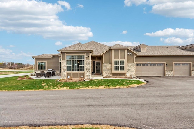 W139S9977 Jay Dr, Muskego, WI 53150 - view of front of house with stone siding, asphalt driveway, an attached garage, a front yard, and stucco siding