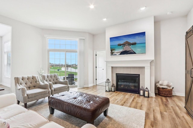 W139S9977 Jay Dr, Muskego, WI 53150 - living area featuring light wood-style floors, baseboards, a fireplace, recessed lighting, and a barn door