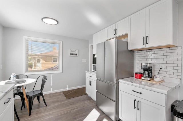 1201 Redwood Dr, Green Bay, WI 54304 - kitchen with freestanding refrigerator, light wood finished floors, decorative backsplash, white cabinetry, and baseboards