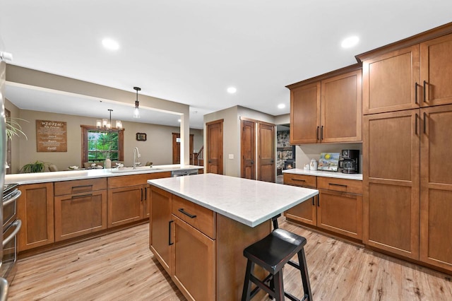 5458 Cascade Dr, West Bend, WI 53095 - kitchen with a sink, brown cabinetry, light wood-type flooring, a breakfast bar area, and hanging light fixtures