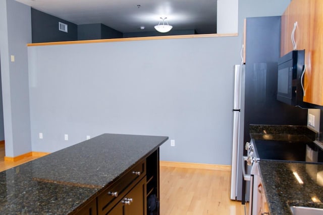 615 W Main St Unit 205, Madison, WI 53703 - kitchen featuring appliances with stainless steel finishes, light wood-style flooring, dark stone countertops, and baseboards