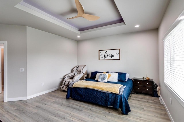 bedroom featuring a tray ceiling, wood finished floors, recessed lighting, a ceiling fan, and baseboards