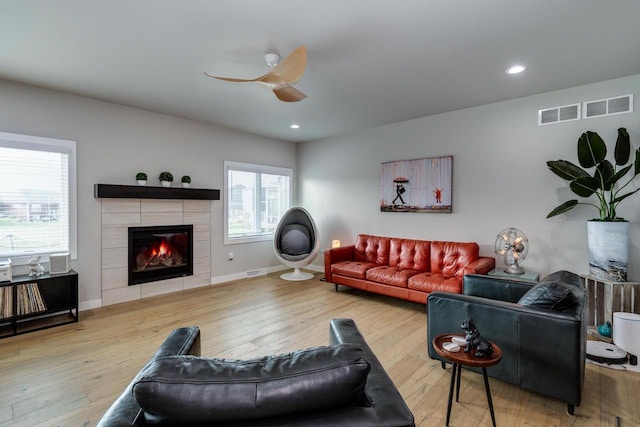 living area with a tile fireplace, hardwood / wood-style flooring, baseboards, a ceiling fan, and recessed lighting