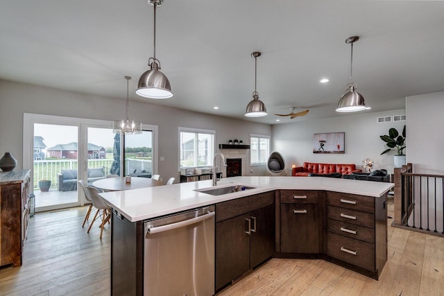 kitchen featuring stainless steel dishwasher, a sink, open floor plan, a fireplace, and recessed lighting