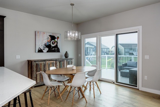 dining space featuring light wood finished floors, baseboards, and a chandelier