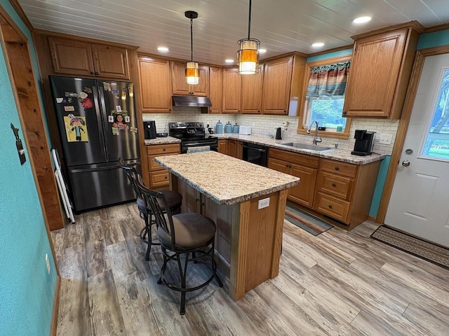 121 W Clark St, Plainfield, WI 54966 - kitchen with black appliances, under cabinet range hood, brown cabinets, a sink, and light wood finished floors