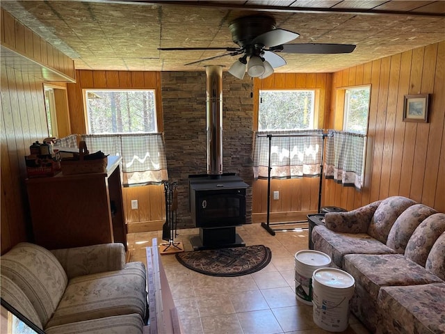 15735 N Park Rd, Butternut, WI 54514 - tiled living area with ceiling fan, a wood stove, and wooden walls