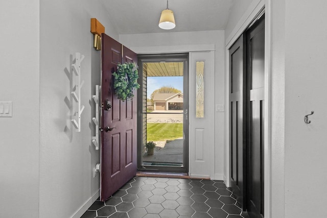 doorway with dark tile patterned floors and baseboards