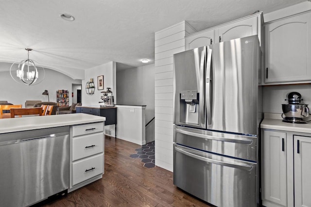 kitchen featuring stainless steel appliances, dark wood-type flooring, light countertops, white cabinetry, and hanging light fixtures