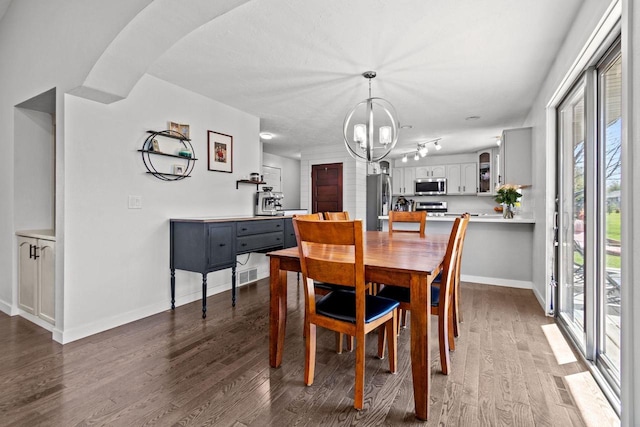 dining room featuring a chandelier, dark wood-style flooring, and baseboards