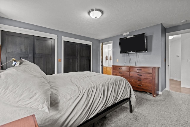 carpeted bedroom featuring baseboards, a textured ceiling, and ensuite bath