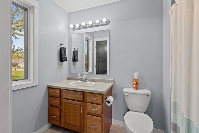 bathroom featuring healthy amount of natural light, baseboards, vanity, and toilet