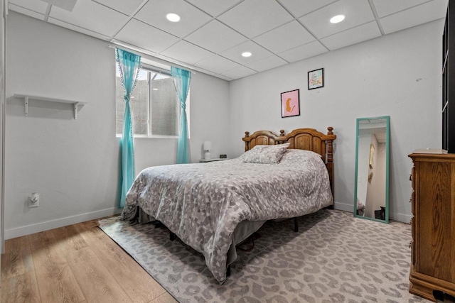 bedroom with wood finished floors, baseboards, a drop ceiling, and recessed lighting