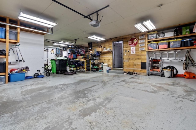 garage with a garage door opener and wood walls
