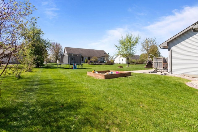 view of green lawn featuring a trampoline