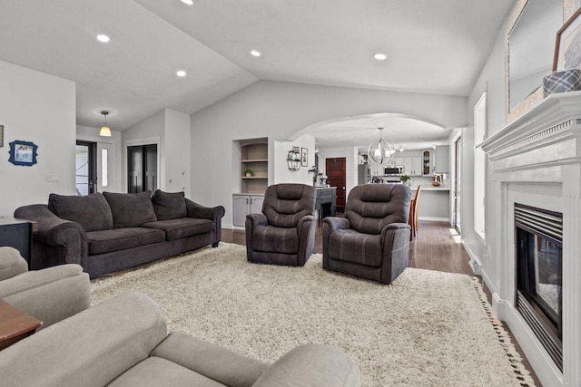 living room with arched walkways, a chandelier, wood finished floors, vaulted ceiling, and recessed lighting
