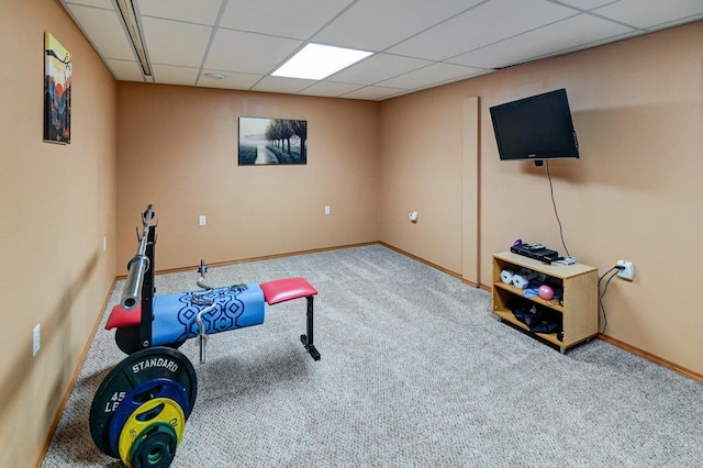 workout area featuring carpet floors, a paneled ceiling, and baseboards