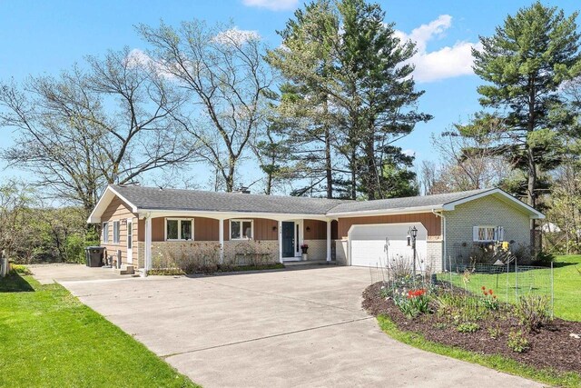 528 Park Ave, Waupaca, WI 54981 - ranch-style house featuring concrete driveway, a garage, a front lawn, and stone siding