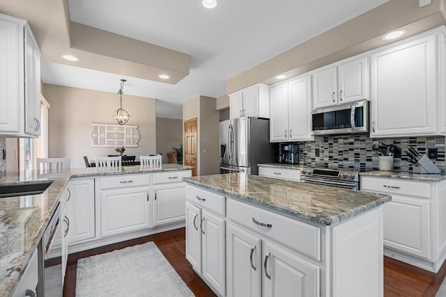 W6928 Westwood Dr, Fond Du Lac, WI 54937 - kitchen featuring appliances with stainless steel finishes, dark wood-style floors, decorative backsplash, a peninsula, and white cabinetry