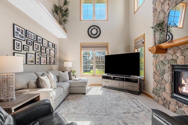 W6928 Westwood Dr, Fond Du Lac, WI 54937 - living area with a stone fireplace, a high ceiling, baseboards, and plenty of natural light