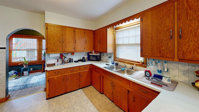 5869 State Highway 27, Sparta, WI 54656 - kitchen with a sink, light countertops, brown cabinetry, backsplash, and black microwave