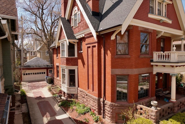 2837 N Marietta Ave, Milwaukee, WI 53211 - view of property exterior featuring brick siding, a detached garage, roof with shingles, an outbuilding, and a chimney