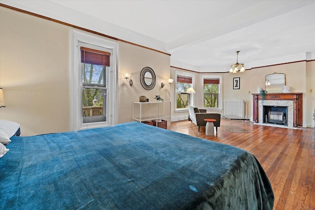 2837 N Marietta Ave, Milwaukee, WI 53211 - bedroom with radiator heating unit, multiple windows, wood finished floors, and a fireplace with flush hearth