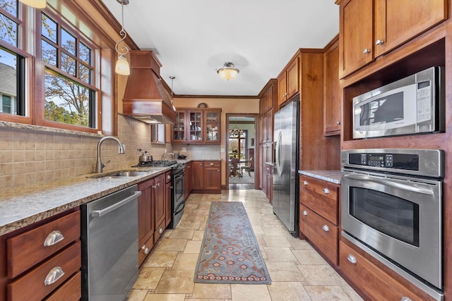 304 16th St, Racine, WI 53403 - kitchen featuring stainless steel appliances, custom exhaust hood, brown cabinets, stone tile flooring, and tasteful backsplash