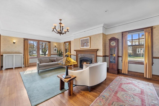 304 16th St, Racine, WI 53403 - living room featuring radiator, wood finished floors, a chandelier, a warm lit fireplace, and crown molding
