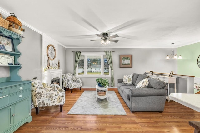 528 High St, Walworth, WI 53184 - living room with crown molding, ceiling fan, a chandelier, wood finished floors, and a warm lit fireplace