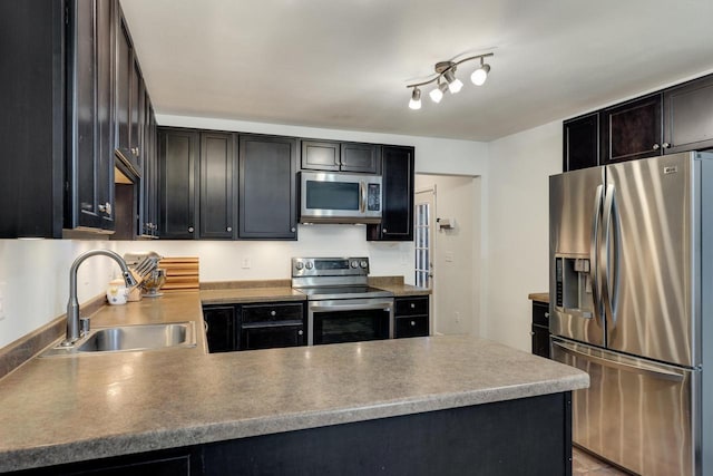 kitchen with stainless steel appliances, a sink, and a peninsula
