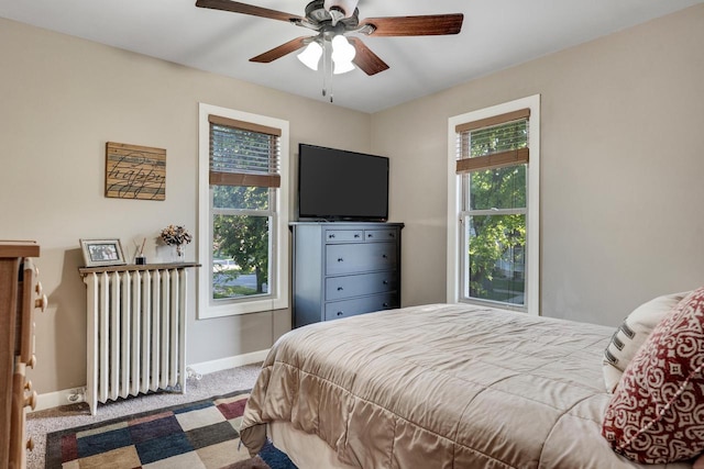 carpeted bedroom with radiator, baseboards, and a ceiling fan