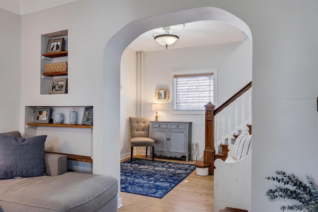 sitting room with arched walkways, wood finished floors, and stairway