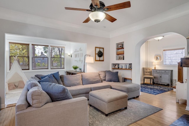 living room featuring arched walkways, hardwood / wood-style flooring, and a ceiling fan