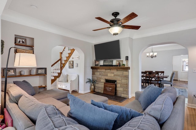 living area with arched walkways, light wood finished floors, a ceiling fan, a chandelier, and radiator