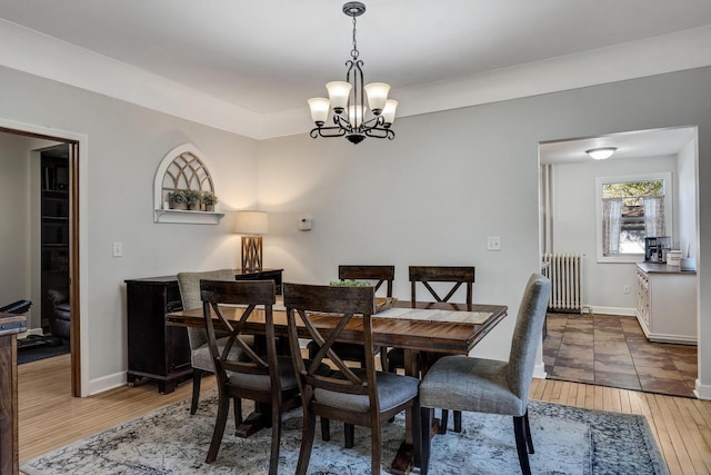 dining space featuring radiator heating unit, a chandelier, light wood-style floors, and baseboards