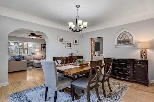 dining room with arched walkways and light wood-type flooring