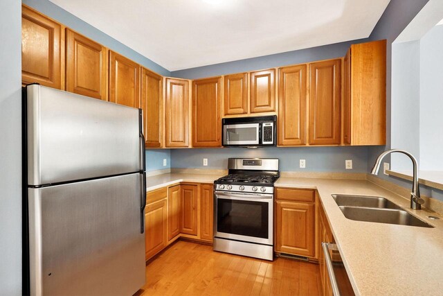 612 N Midvale Blvd, Madison, WI 53705 - kitchen with appliances with stainless steel finishes, a sink, light wood-type flooring, light countertops, and brown cabinets