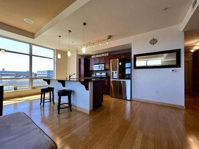 106 W Seeboth St Unit 503, Milwaukee, WI 53204 - kitchen with appliances with stainless steel finishes, dark countertops, a kitchen breakfast bar, tasteful backsplash, and wood finished floors