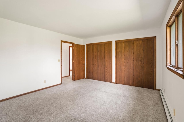 9 Sandalwood Ct, Wind Point, WI 53402 - unfurnished bedroom featuring a baseboard heating unit, two closets, carpet floors, and baseboards