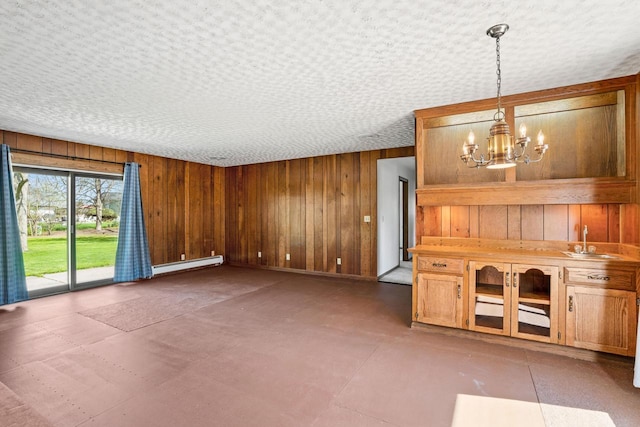9 Sandalwood Ct, Wind Point, WI 53402 - unfurnished living room featuring wood walls, a sink, a baseboard heating unit, and a chandelier