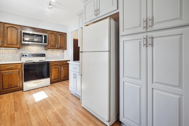 1820 Sampson St, Wisconsin Rapids, WI 54494 - kitchen with stainless steel microwave, range with electric stovetop, freestanding refrigerator, light wood-type flooring, and tasteful backsplash