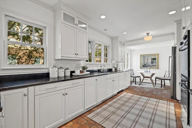 3468 N Summit Ave, Milwaukee, WI 53211 - kitchen featuring white cabinetry, black oven, a sink, glass insert cabinets, and crown molding