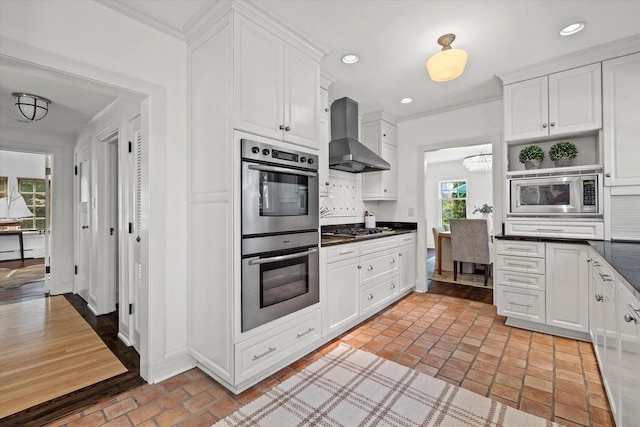 3468 N Summit Ave, Milwaukee, WI 53211 - kitchen featuring appliances with stainless steel finishes, wall chimney range hood, dark countertops, brick floors, and white cabinets
