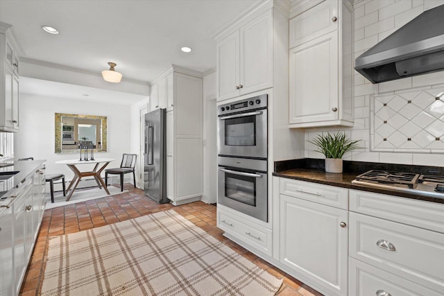3468 N Summit Ave, Milwaukee, WI 53211 - kitchen with appliances with stainless steel finishes, wall chimney exhaust hood, white cabinetry, dark countertops, and backsplash